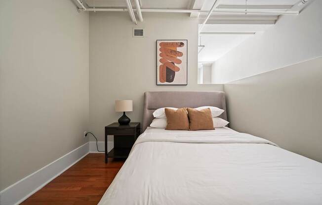 A bedroom with a bed, nightstand, and lamp.