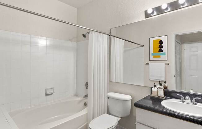 A white bathroom with a white toilet, sink, and bathtub.