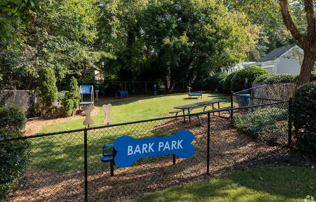 A sign that says Bark Park is in front of a fence.