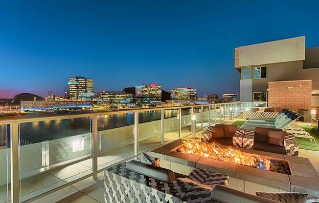 A rooftop patio with a pool and a view of the city at night.