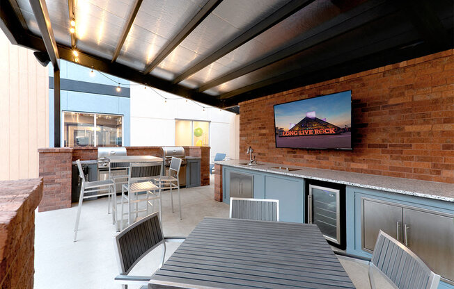 a patio with a table and chairs and a tv at Aster Apartments, Beachwood, OH