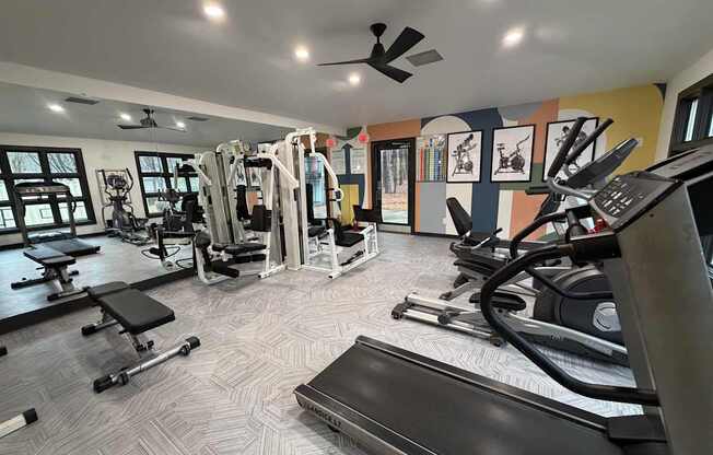 A gym with a variety of equipment including treadmills, weights, and exercise machines.