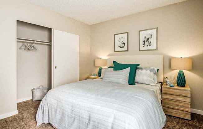 A bedroom with a bed, nightstands, and two pictures on the wall.