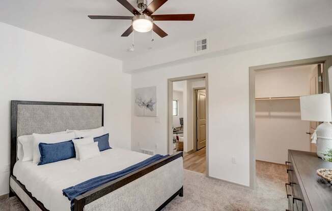 A bedroom with a bed, a ceiling fan, and a nightstand.