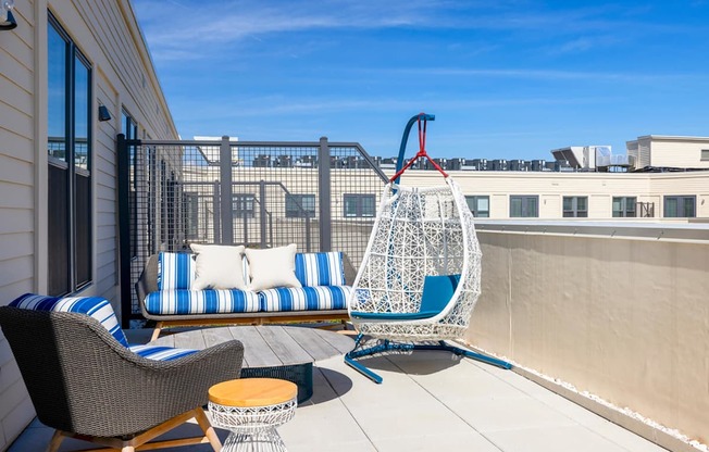 A patio with a hanging chair and a couch.