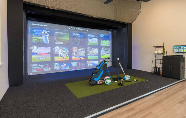 a room with a golf simulator and a projection screen