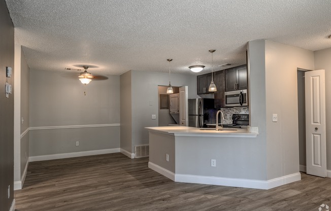 an empty living room with a kitchen and a counter top