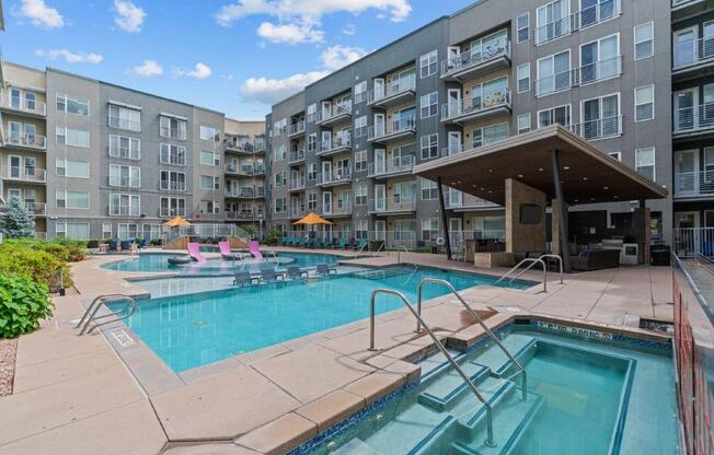 a swimming pool and hot tub in front of an apartment building