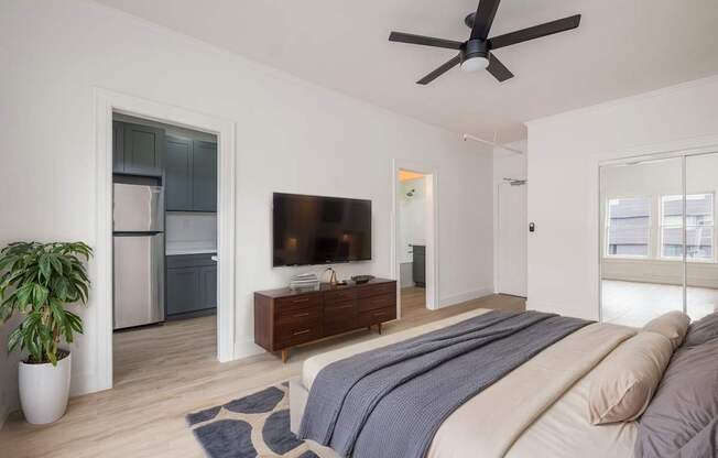 A bedroom with a bed, a television, and a plant at Westmore Manor Apartments, Los Angeles, CA