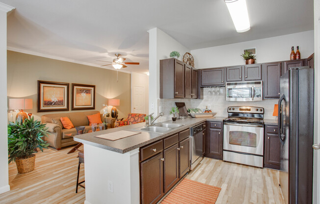 View of Kitchen with Plank-Wood Flooring, Stainless Steel Appliances, and View of Living Room at Raveneaux Apartments