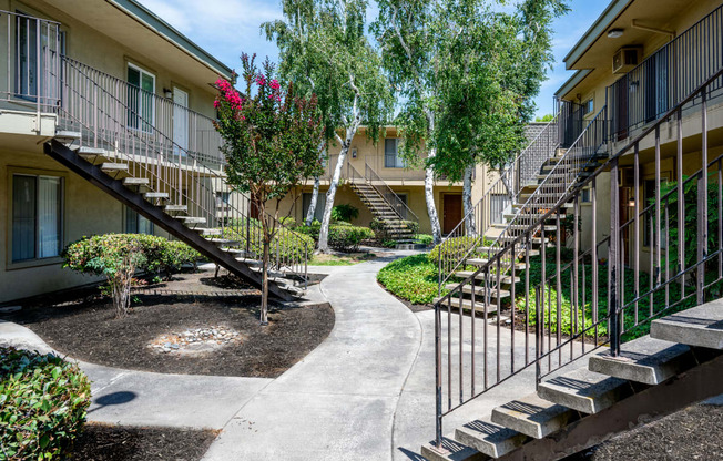 a courtyard with stairs and trees in front of an apartment building