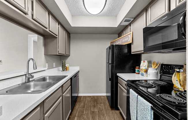 A kitchen with a black refrigerator and a white sink.