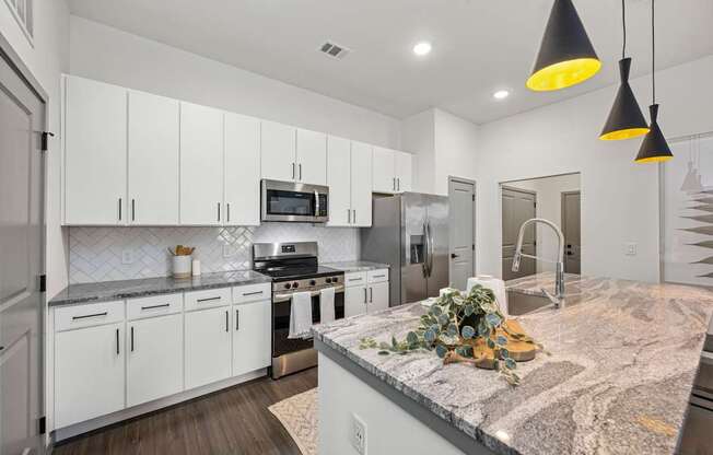 A kitchen with white cabinets and a marble countertop.
