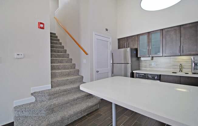 a kitchen with a white counter next to a stairwell