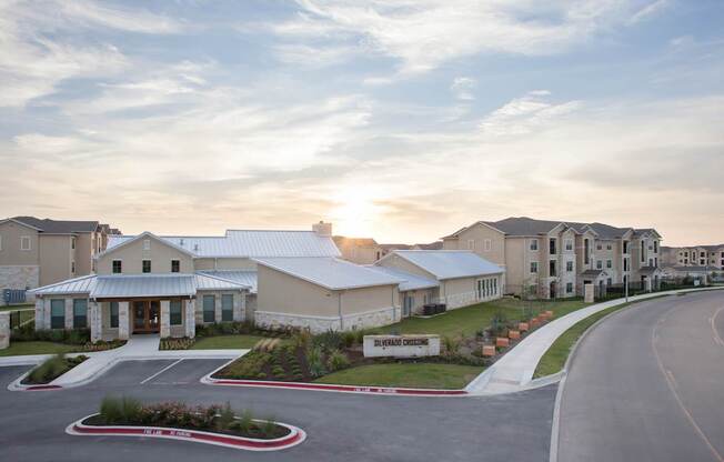 A sunset view of a building with a parking lot in front.