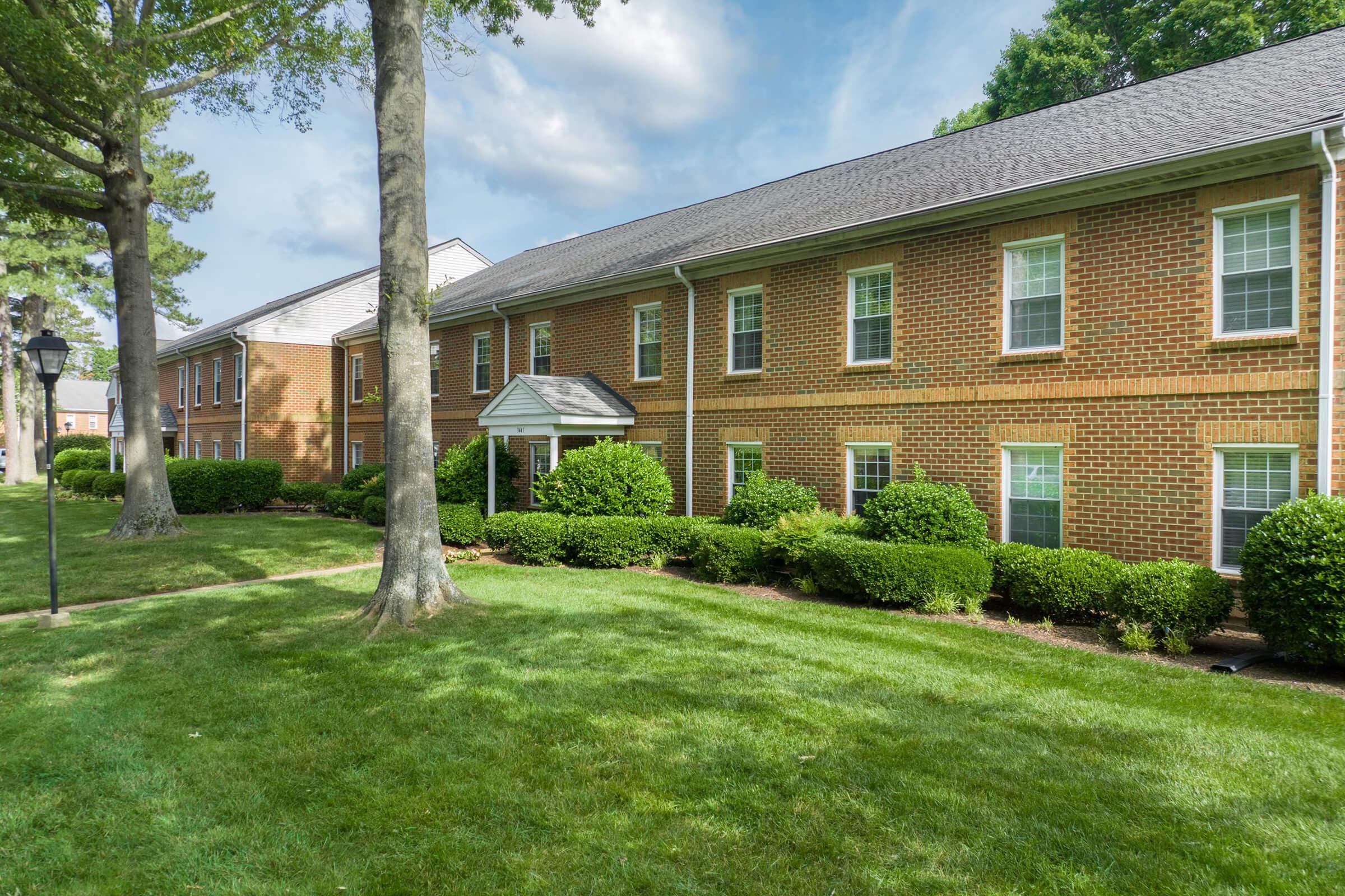 a large brick building with grass in front of a house