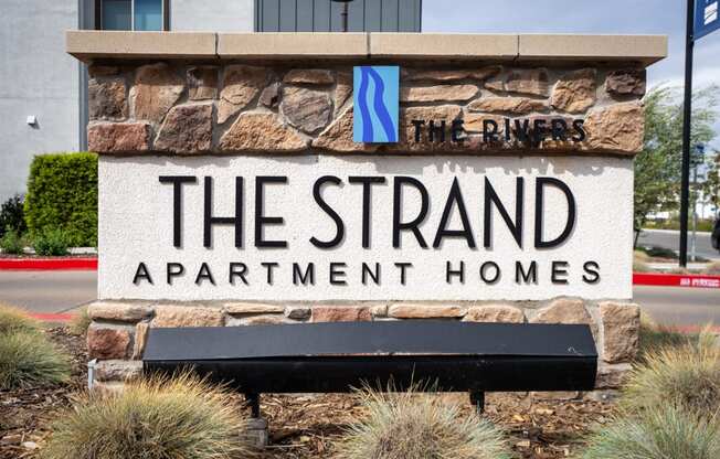 A sign for The Strand Apartment Homes is displayed in front of a building.