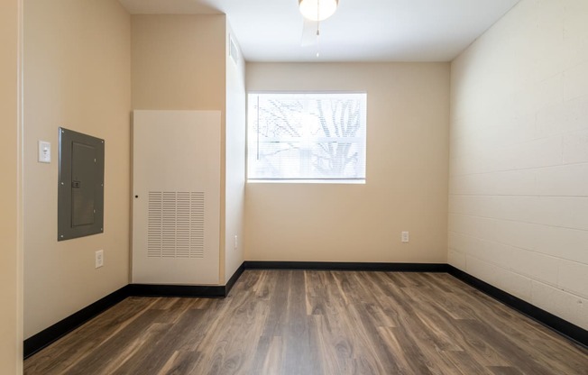 an empty room with wood floors and a window