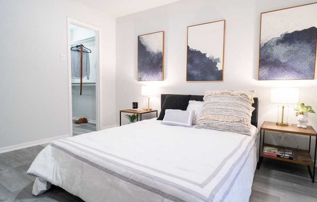 a bedroom with a white bed and paintings on the wall