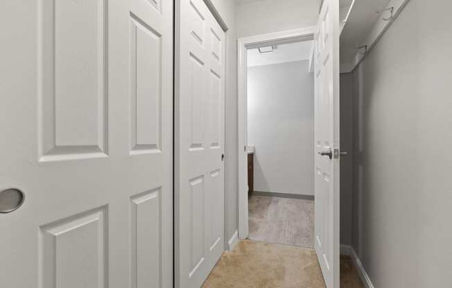 Hallway with white doors and a door to a bathroom  at the River, Manchester, 03102