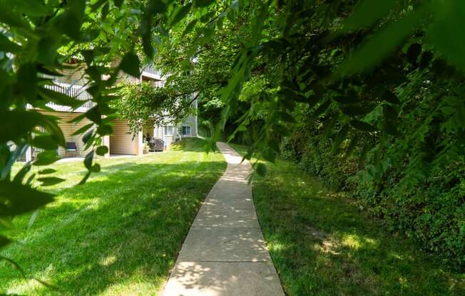 a walkway through the grass in front of a house