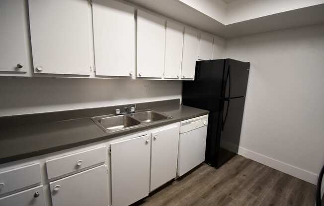 a kitchen with white cabinets and a black refrigerator