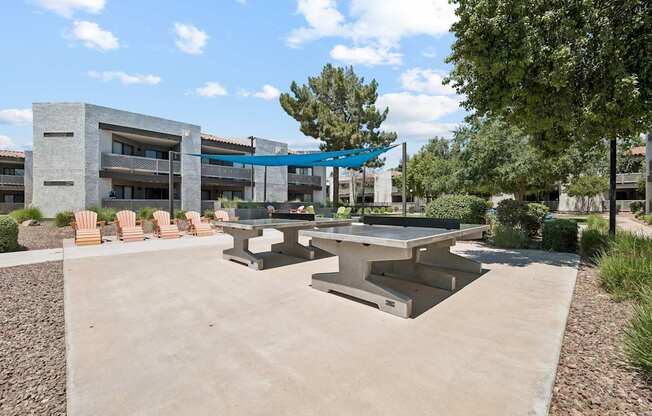 A concrete patio with a table and chairs in front of a building.