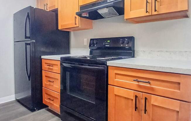 A kitchen with black appliances and wooden cabinets.