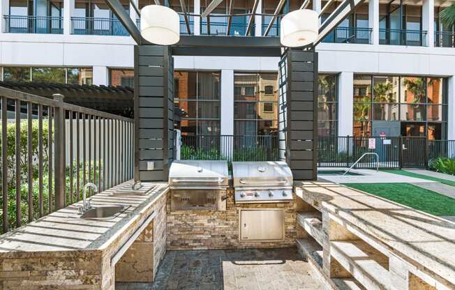 a patio with a grill and two sinks in front of a building