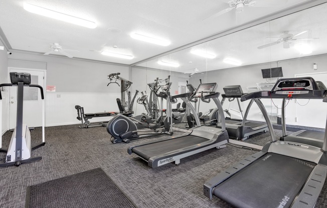 A gym with treadmills, elliptical machines, and other exercise equipment.