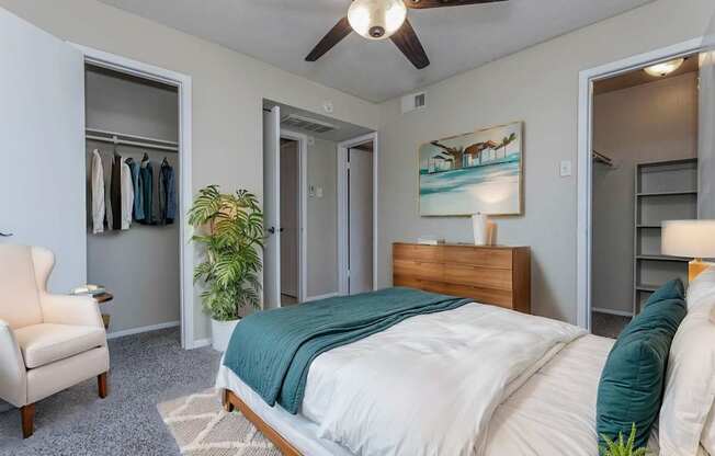 A bedroom with a bed, chair, and painting on the wall.