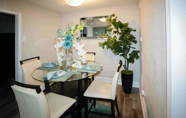 A dining table with chairs and a vase with flowers.