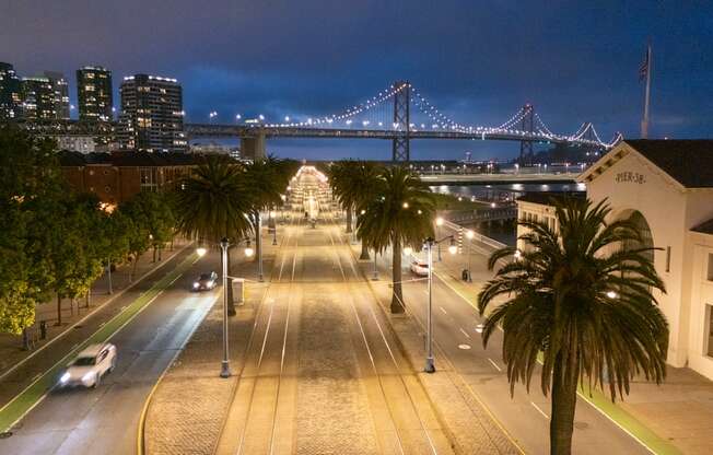 A city street at night with a bridge in the background.