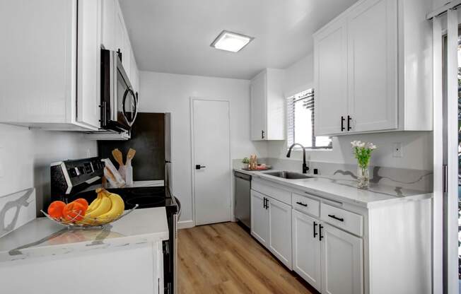 a kitchen with white cabinets and a bowl of fruit on the counter