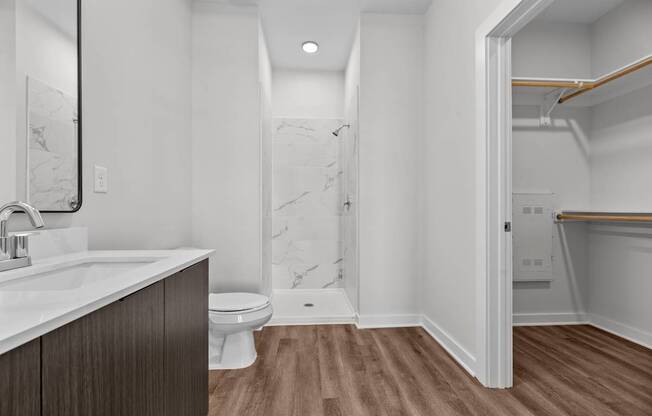 A bathroom with a toilet, sink, and marble wall.