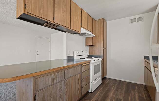 A kitchen with wooden cabinets and a white stove top oven.