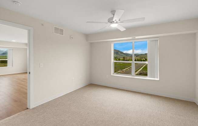A room with a window showing a view of a mountain and a fan on the ceiling.