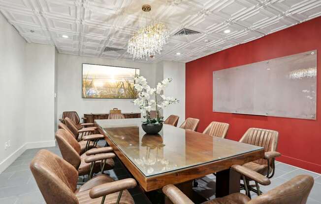 A long wooden table is surrounded by chairs in a room with a chandelier hanging from the ceiling.