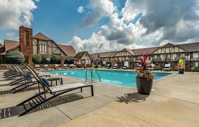 A pool area with sun loungers and a building in the background