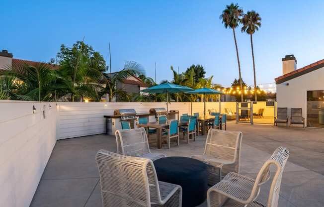 a rooftop patio with tables and chairs and palm trees at Laguna Gardens Apts., Laguna Niguel, California