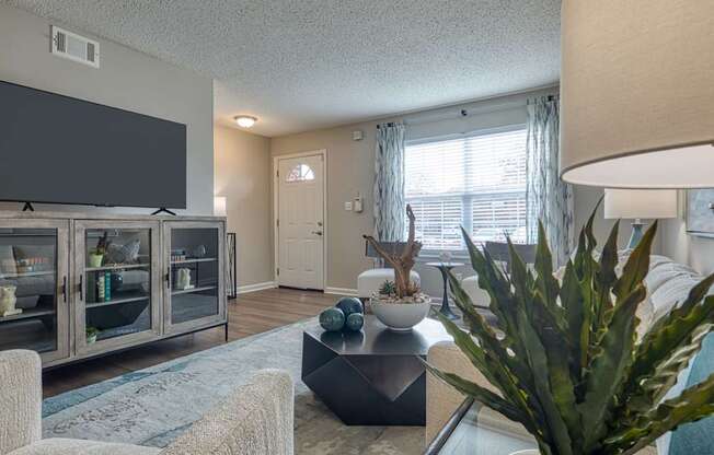 A living room with a flat screen TV and a glass table.