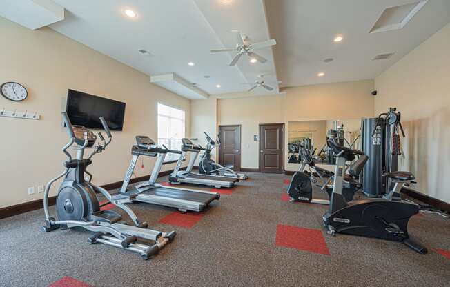 a gym with treadmills and weights and a tv