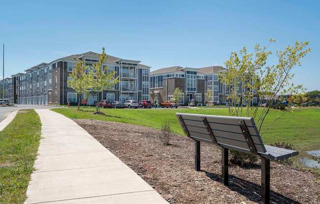 A bench is on the side of a concrete walkway.