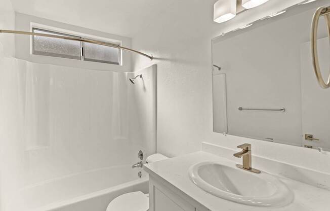A white bathroom with a toilet, sink, and tub.