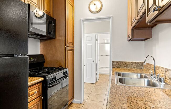 A kitchen with a black fridge, microwave, and stove.