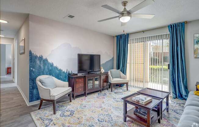 A living room with a television, two chairs, a coffee table, and a rug.
