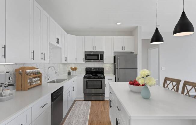 a large white kitchen with stainless steel appliances and white cabinets