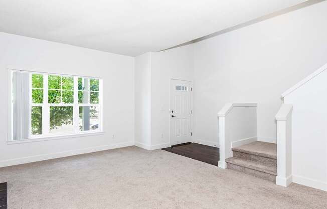 A living room with a staircase and a door at The Landing Apartments and Townhomes, Oregon, 97045