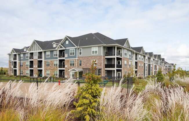 an apartment complex with tall grass in the foreground