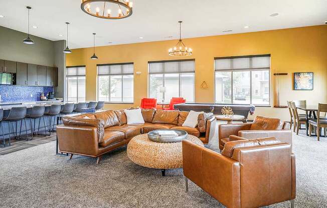 A clubhouse TV lounge with brown leather couches and chairs.
